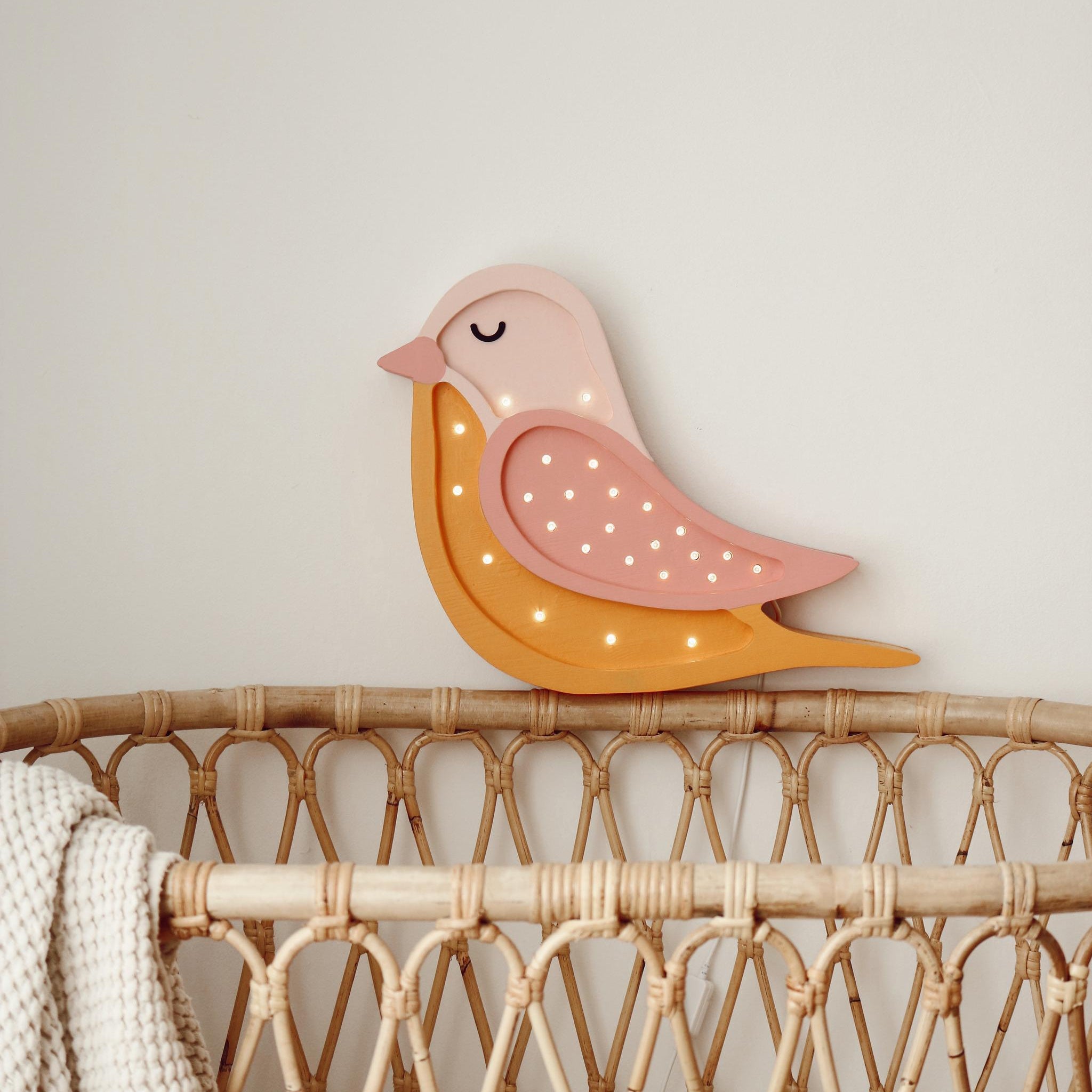 Bird lamp on a wicker crib in a baby nursery
