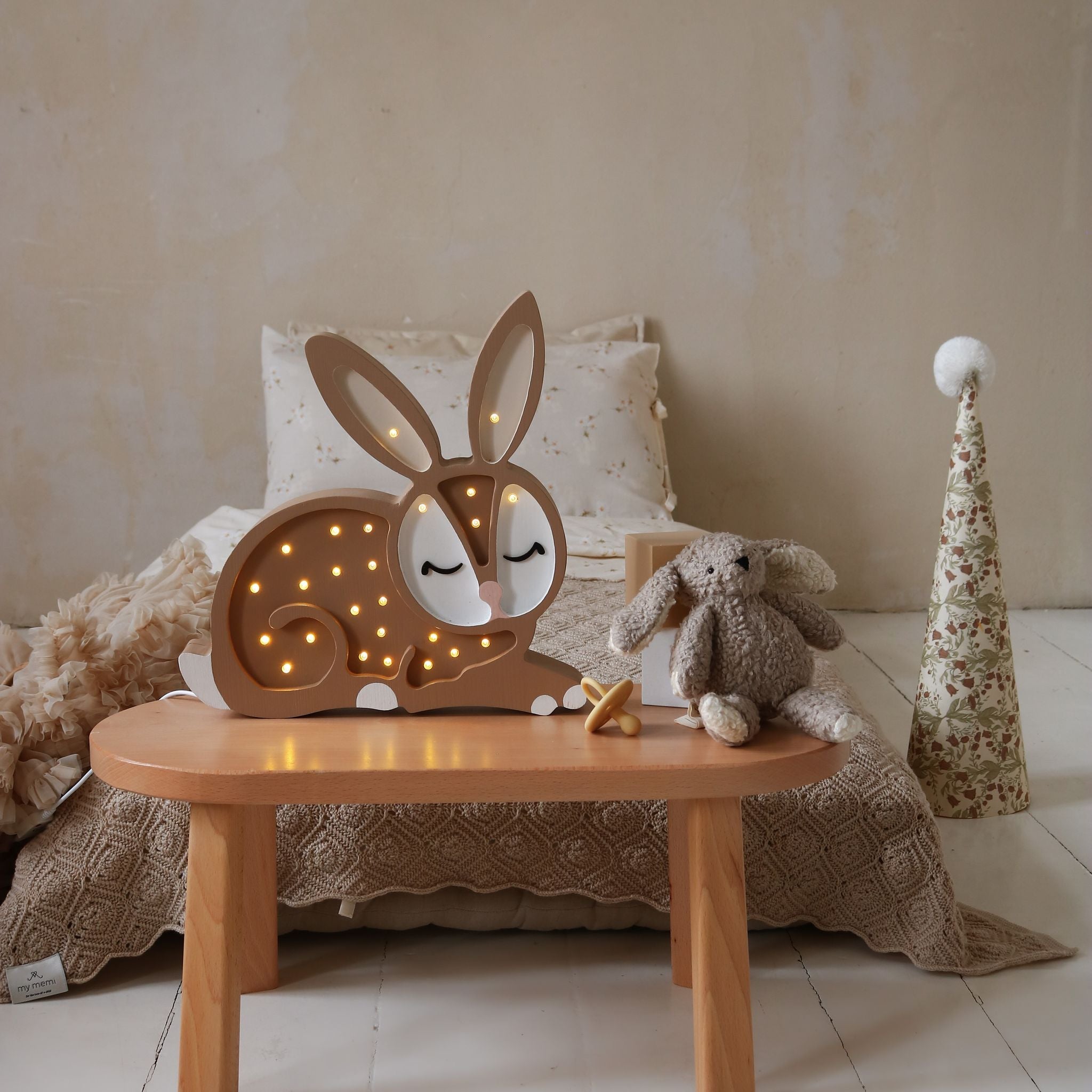 Little Lights wooden Bunny night light on a table in a cozy room with soft lighting.