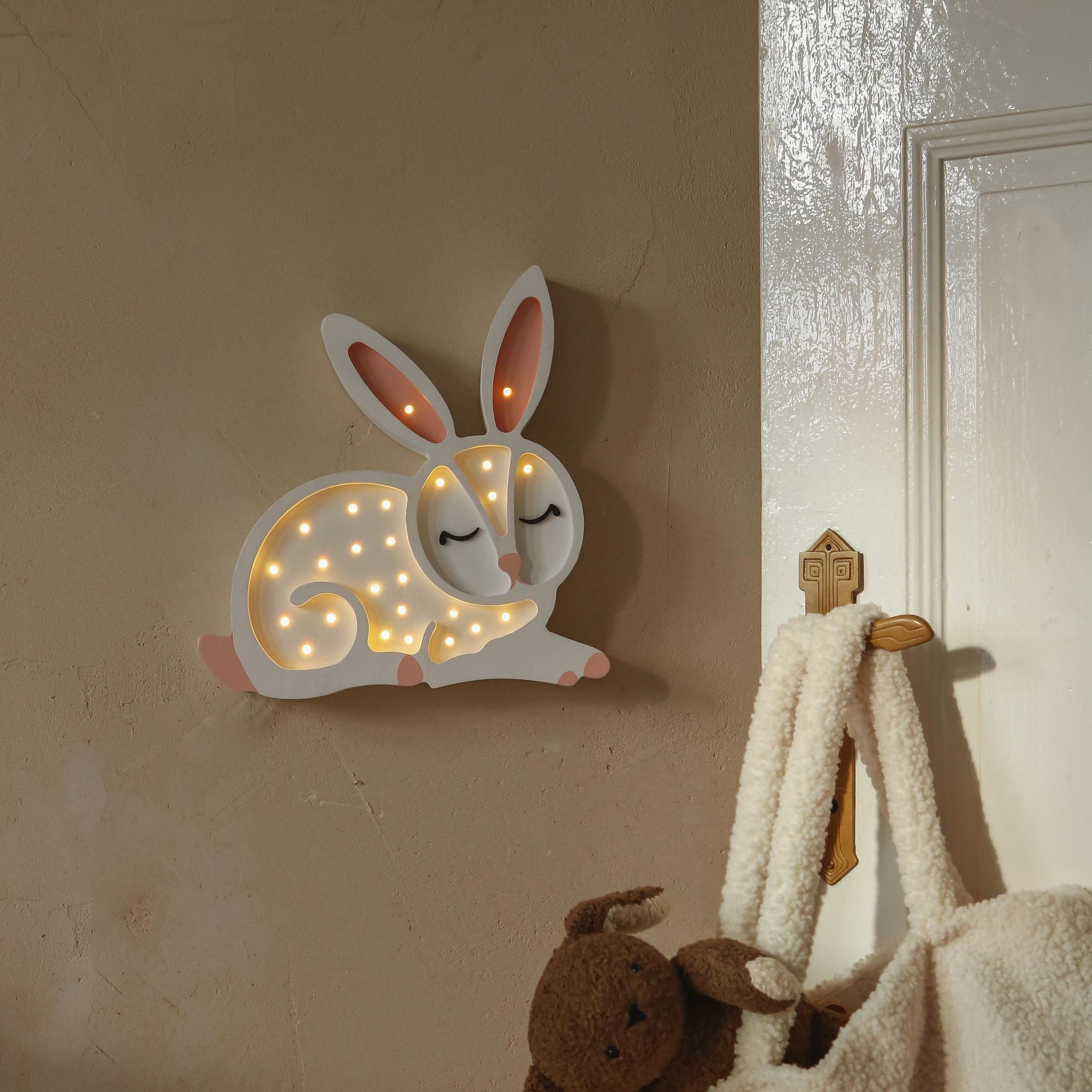 Little Lights white Bunny night light on a wall in a child's room.