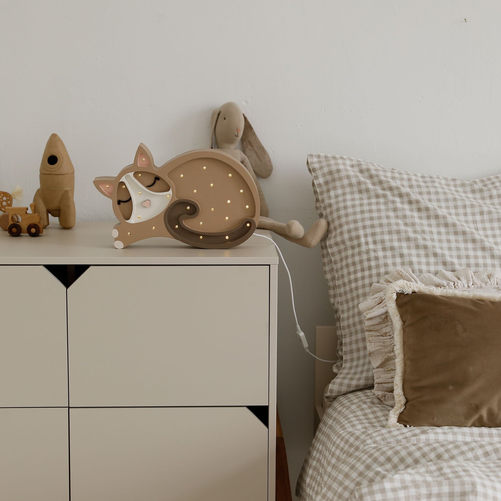 Little Light Cat Night Light Cappuccino on a dresser by a bed in a kid's room