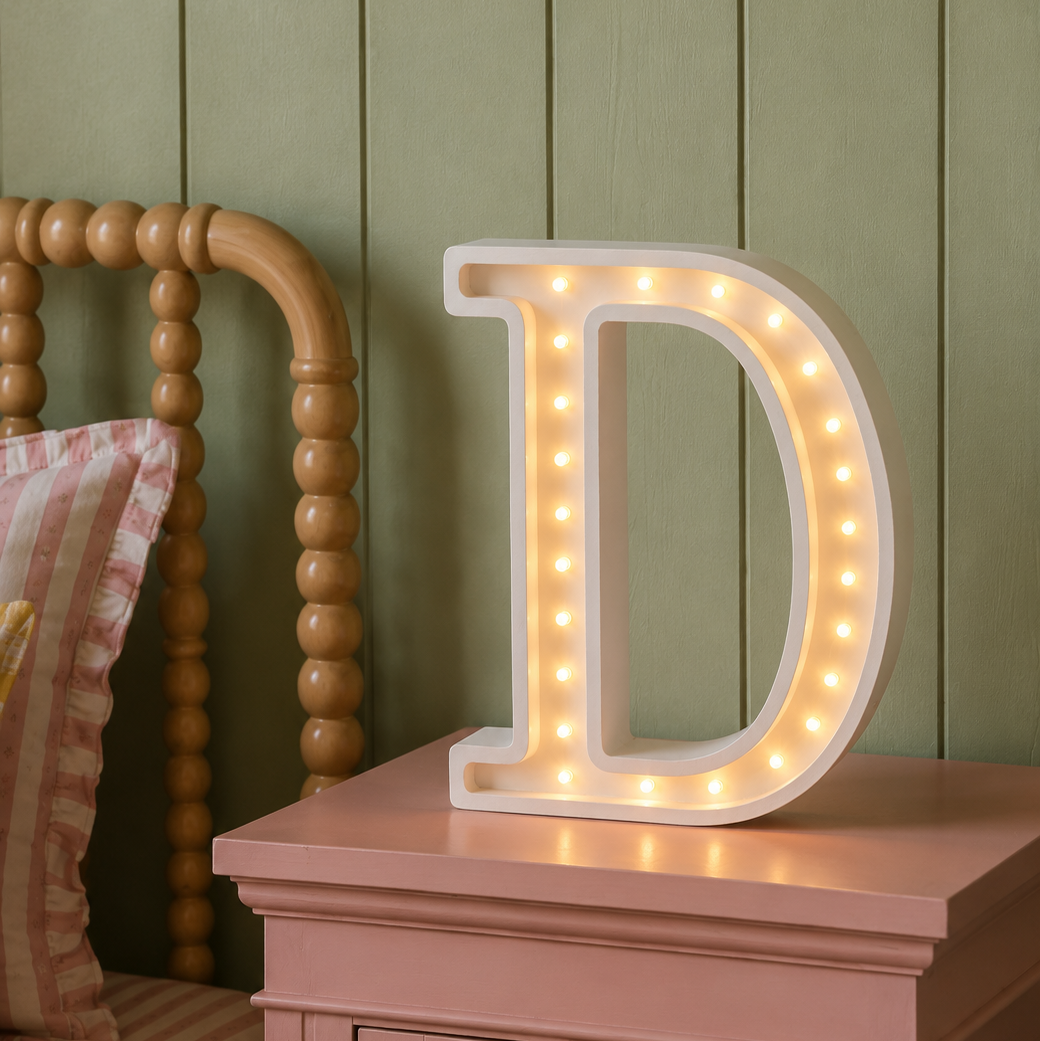 Little Lights Wooden Custom Made D Night Light glowing on a pink night stand in a girl's bedroom