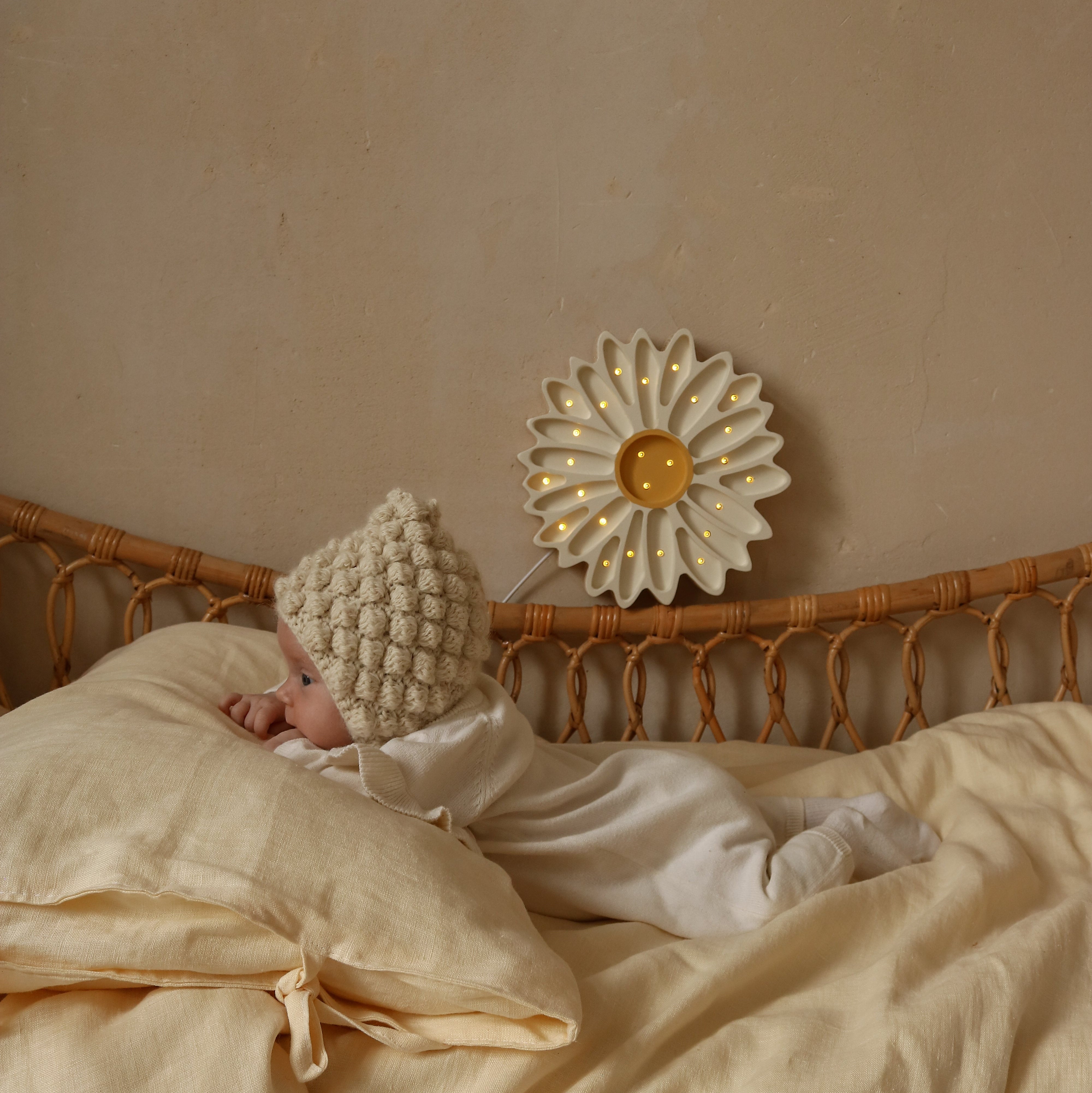 Little Lights White Daisy Lamp glowing in a baby nursery