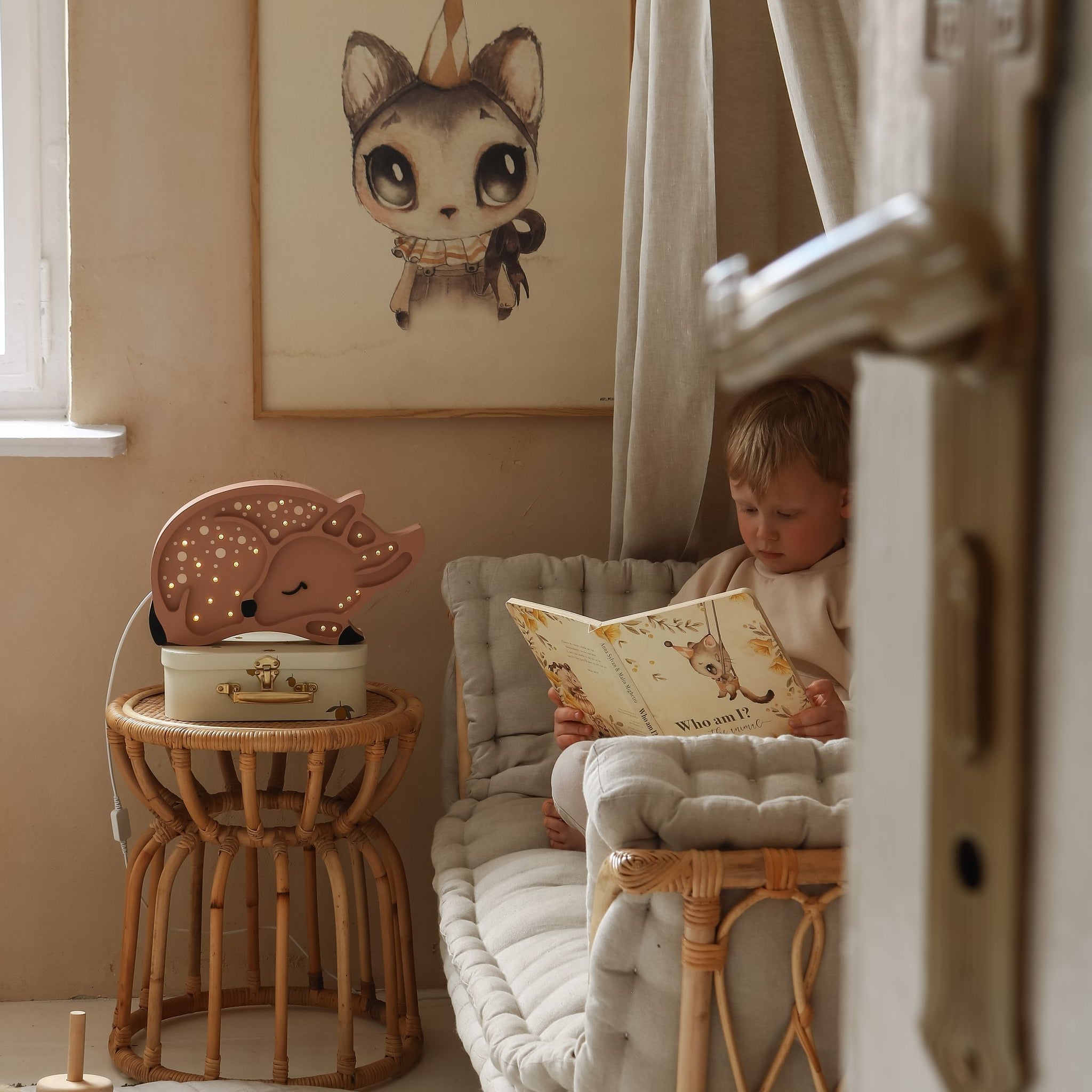 Child reading a book in a cozy room next to Little Lights Deer Lamp