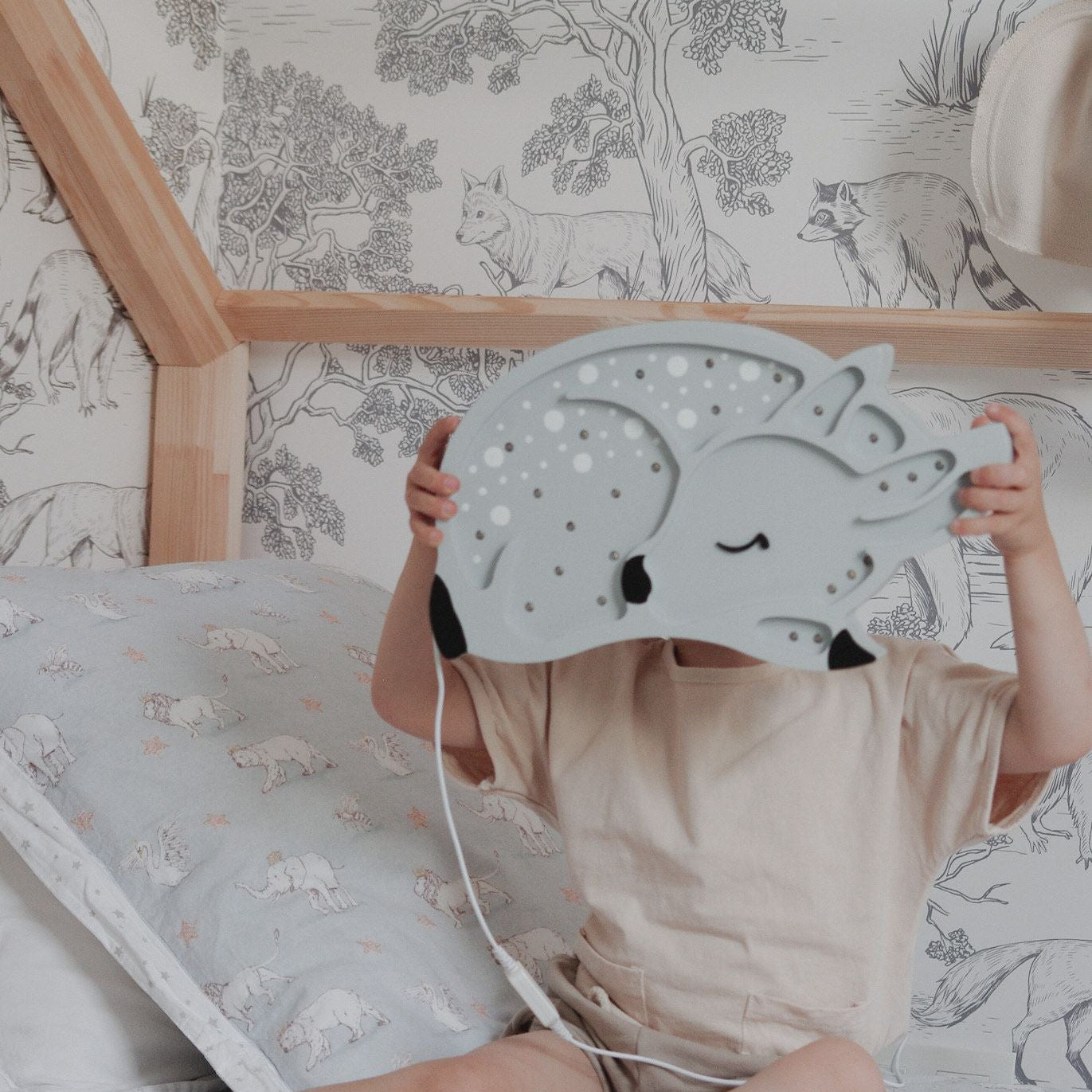 Boy holding Little Lights Grey Deer Lamp sitting in his room