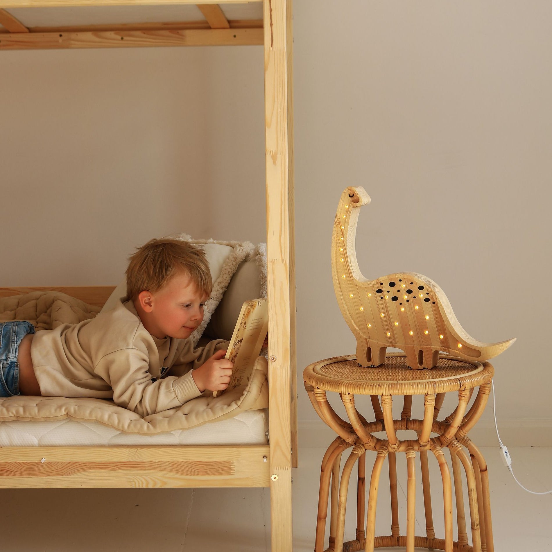 Boy reading a book next to Little Lights Dino Diplodocus Lamp Jurassic Wood