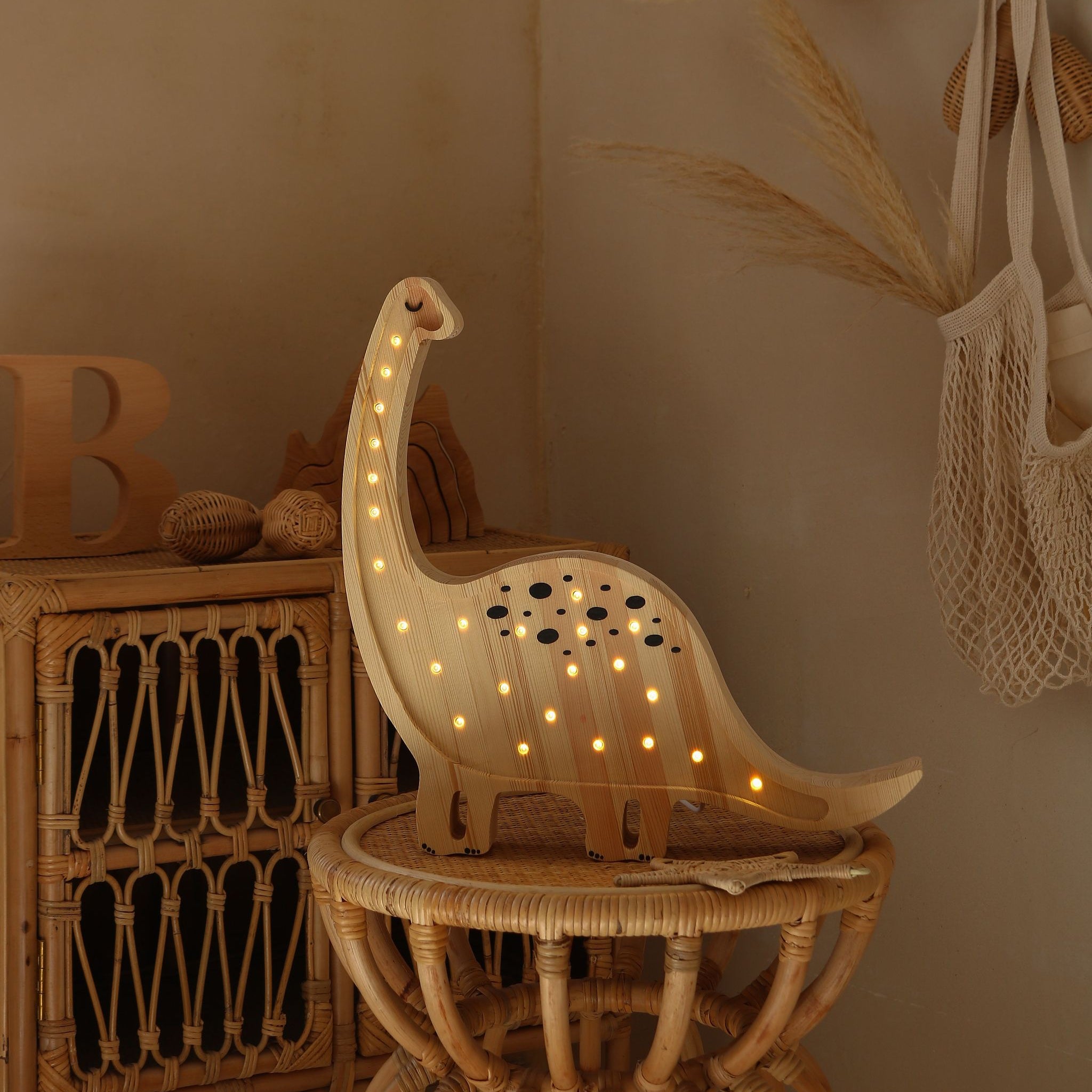 Wooden Little Lights Dinosaur lamp on a small table in a neutral nursery