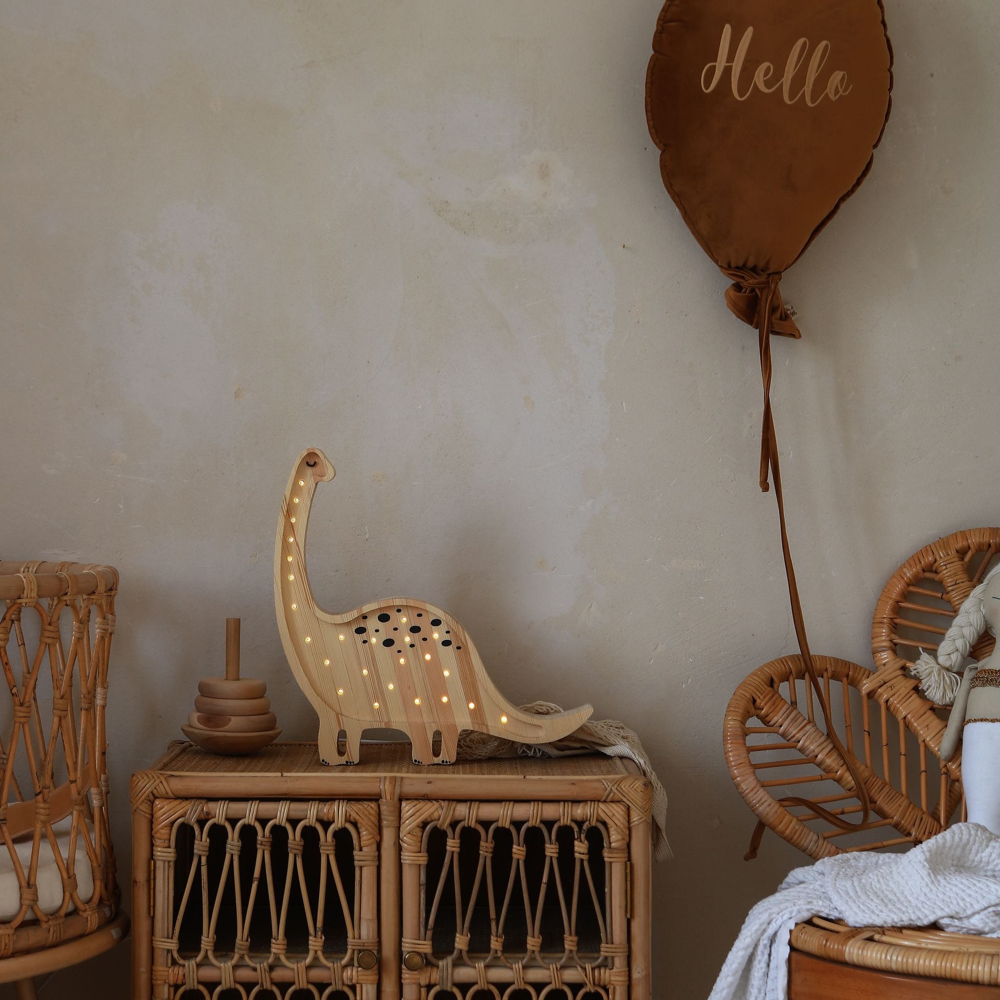 Little Lights Jurassic Wood Dinosaur Diplodocus night light on a dresser next to a baby wicker crib