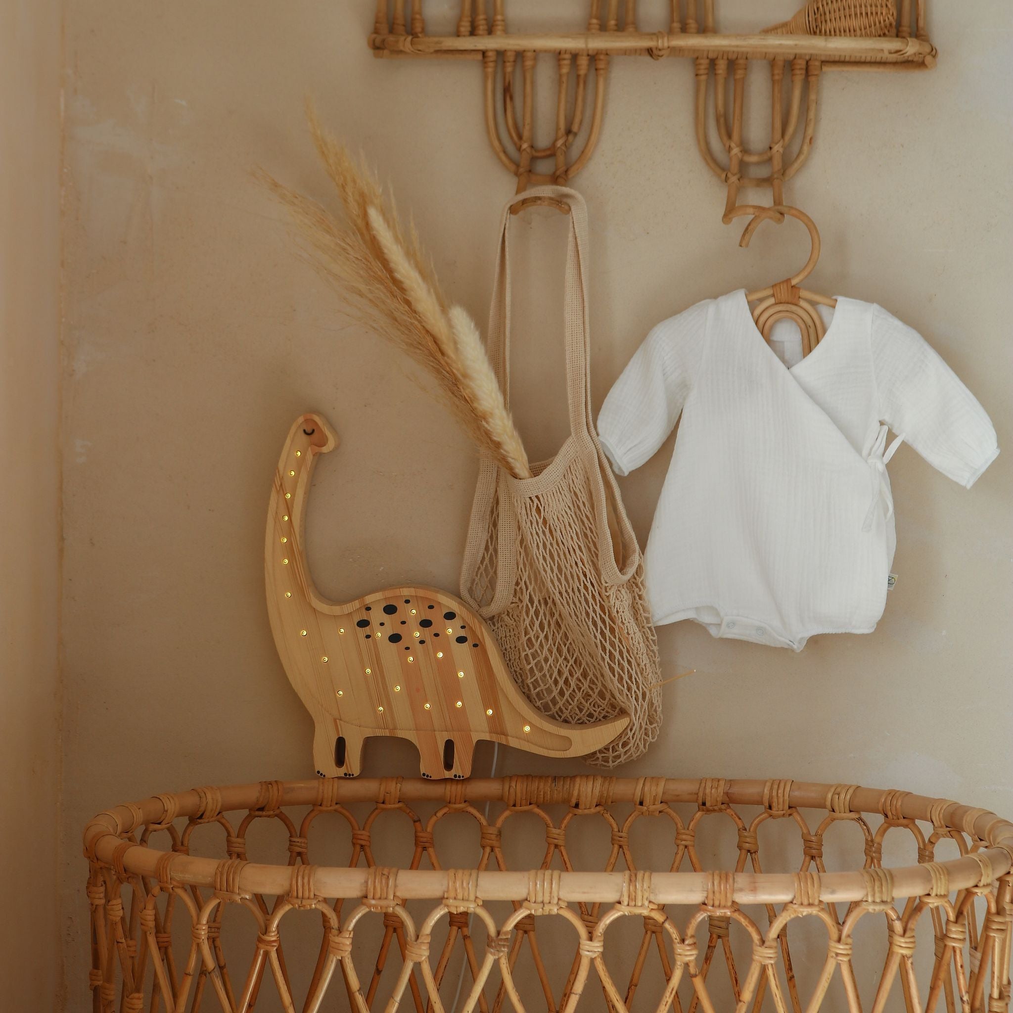 Wicker crib with Wooden Little Lights Dino Diplodocus lamp glowing softly