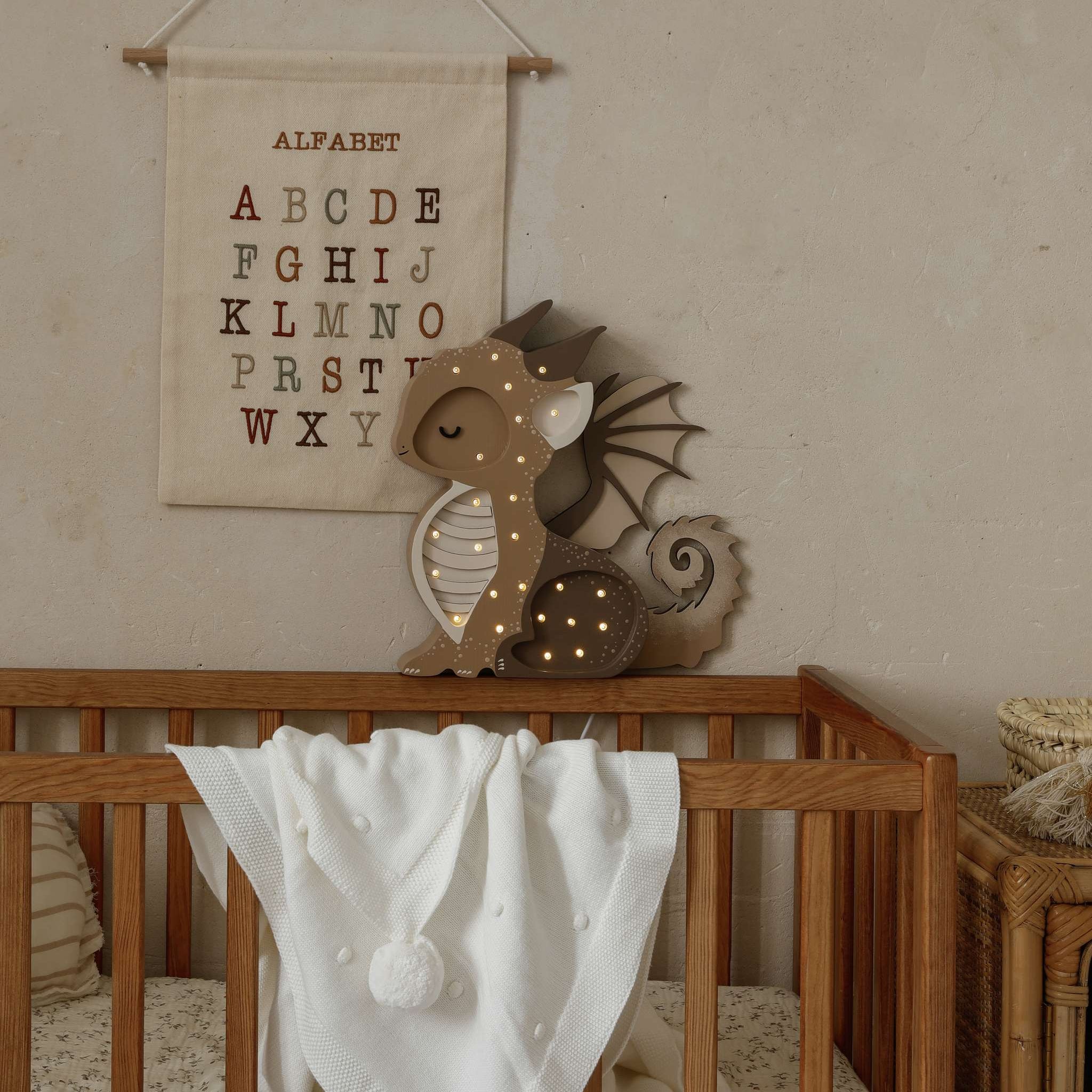 Little Lights Brwon Baby Dragon Night Light glowing softly in a baby nursery