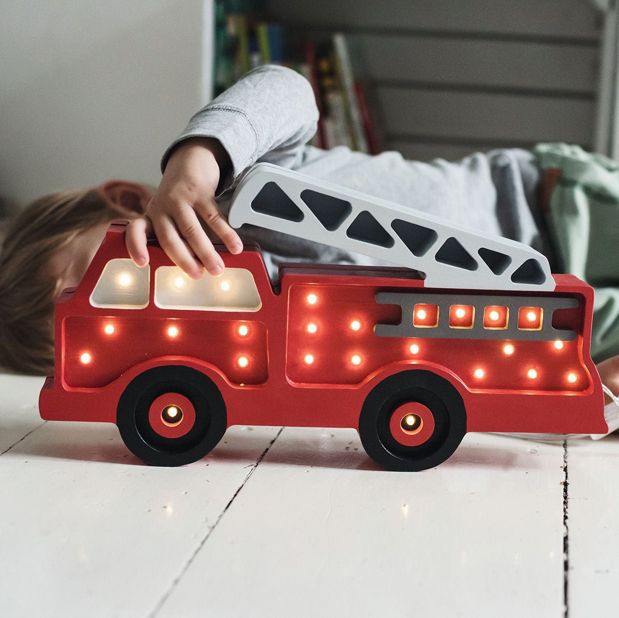 A boy holding Little Lights Fire Truck lamp