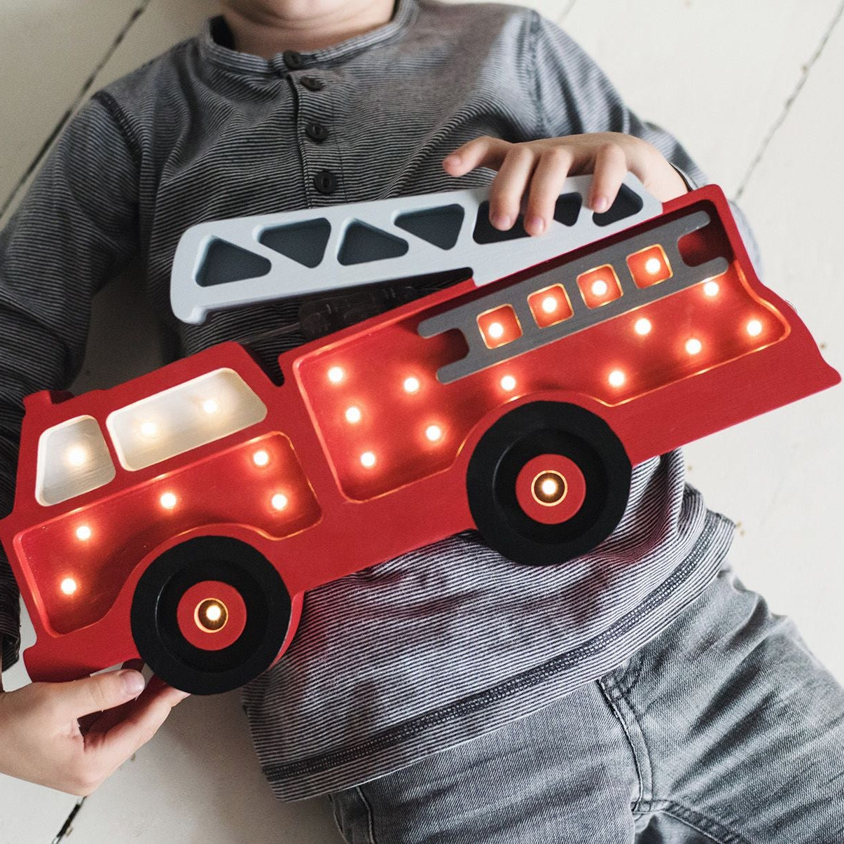 A boy holding Little Liights Red Fire Truck Lamp
