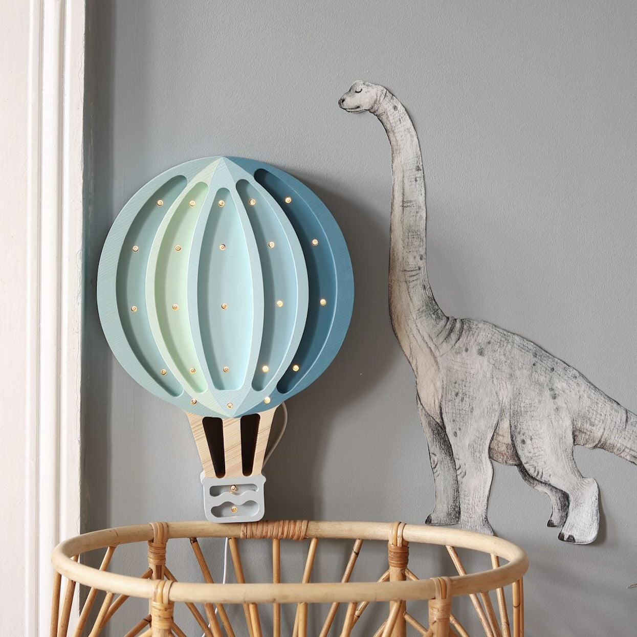 Little Lights blue Hot Air Balloon lamp next to a wicker baby crib