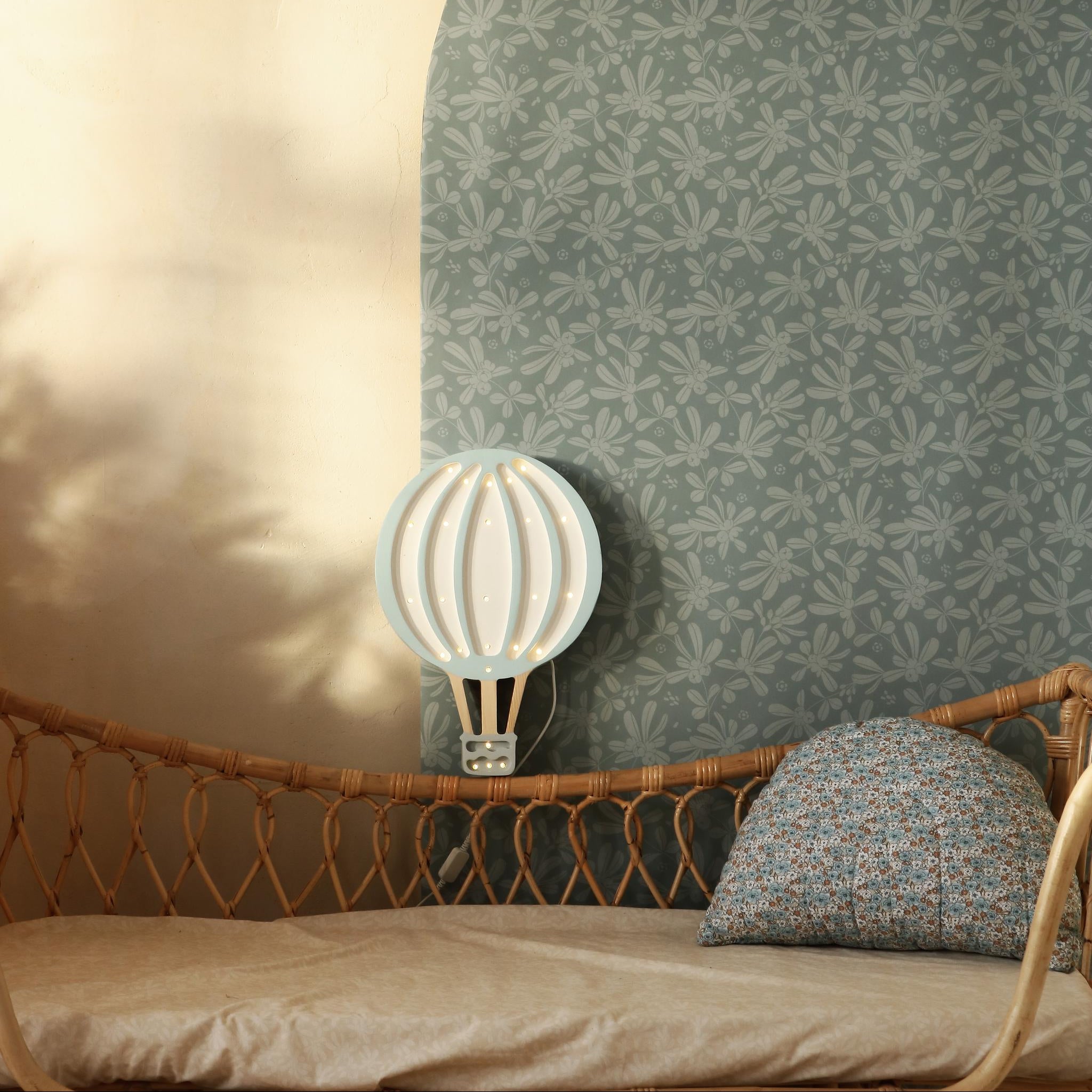 Little Lights Blue Sky Hot Air Balloon by a wicker bed in a baby room