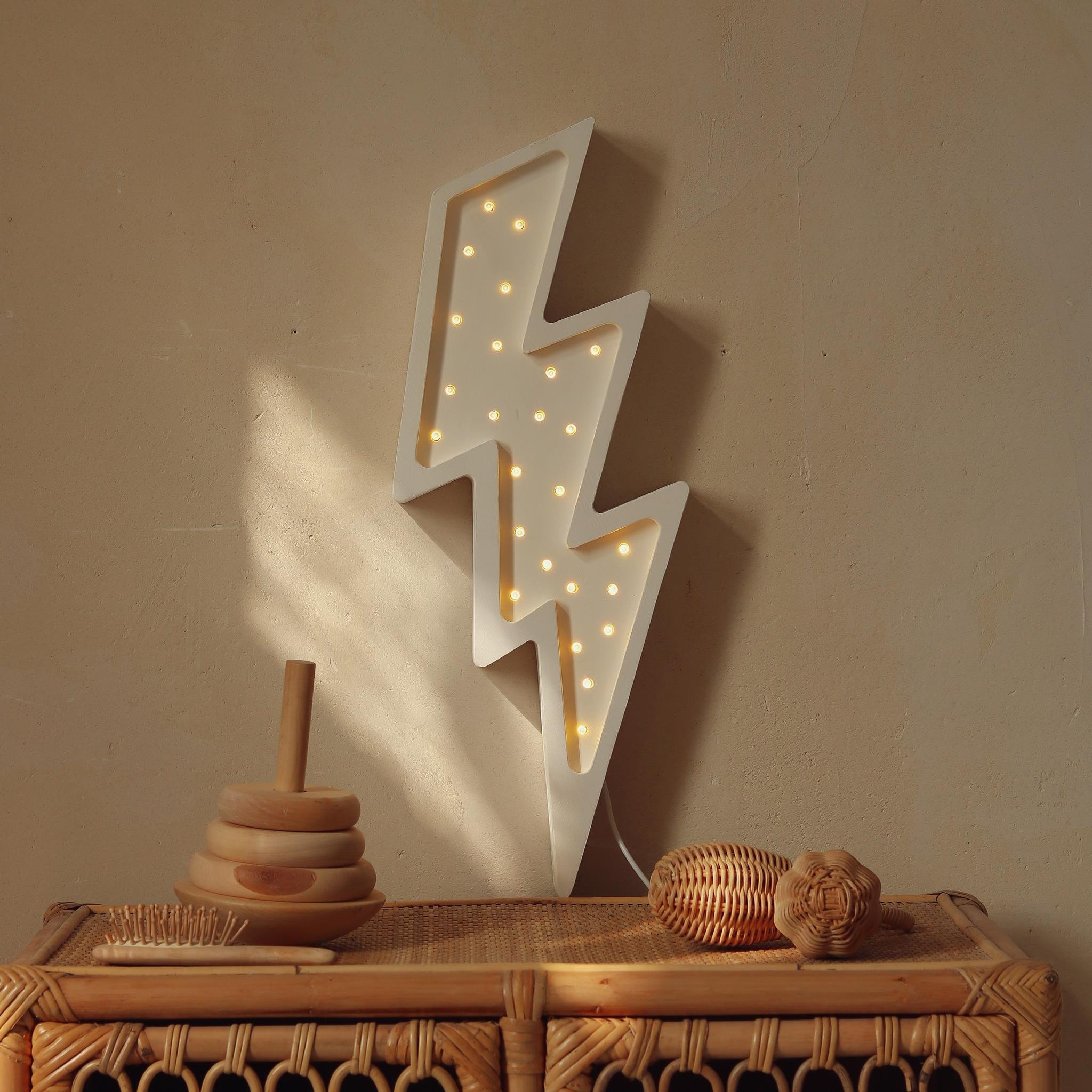 White Lightning Bolt Lamp on the wall near a dresser in a baby room