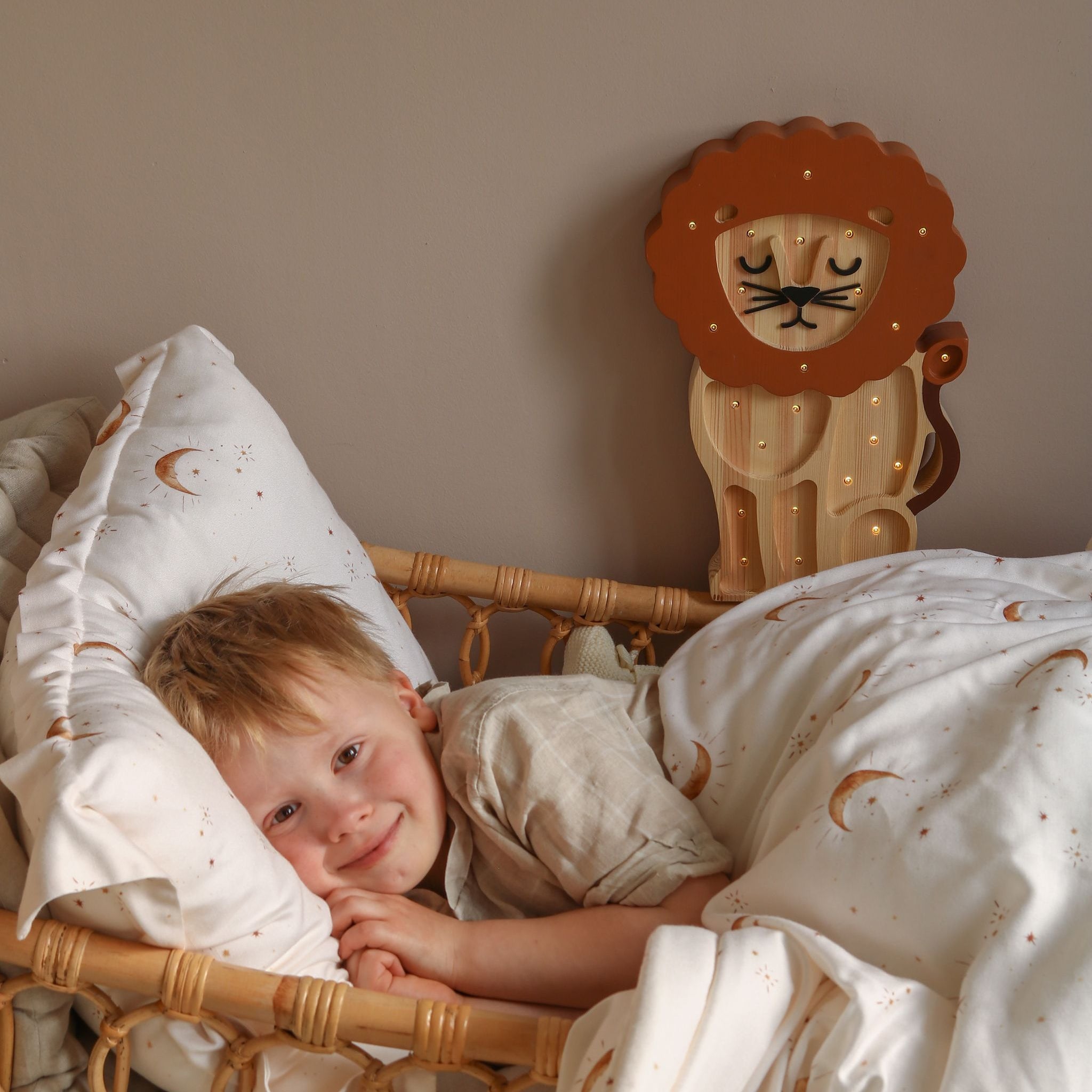Boy lying in a bed with the Little Lights Lion Lamp softly glowing in kid's room