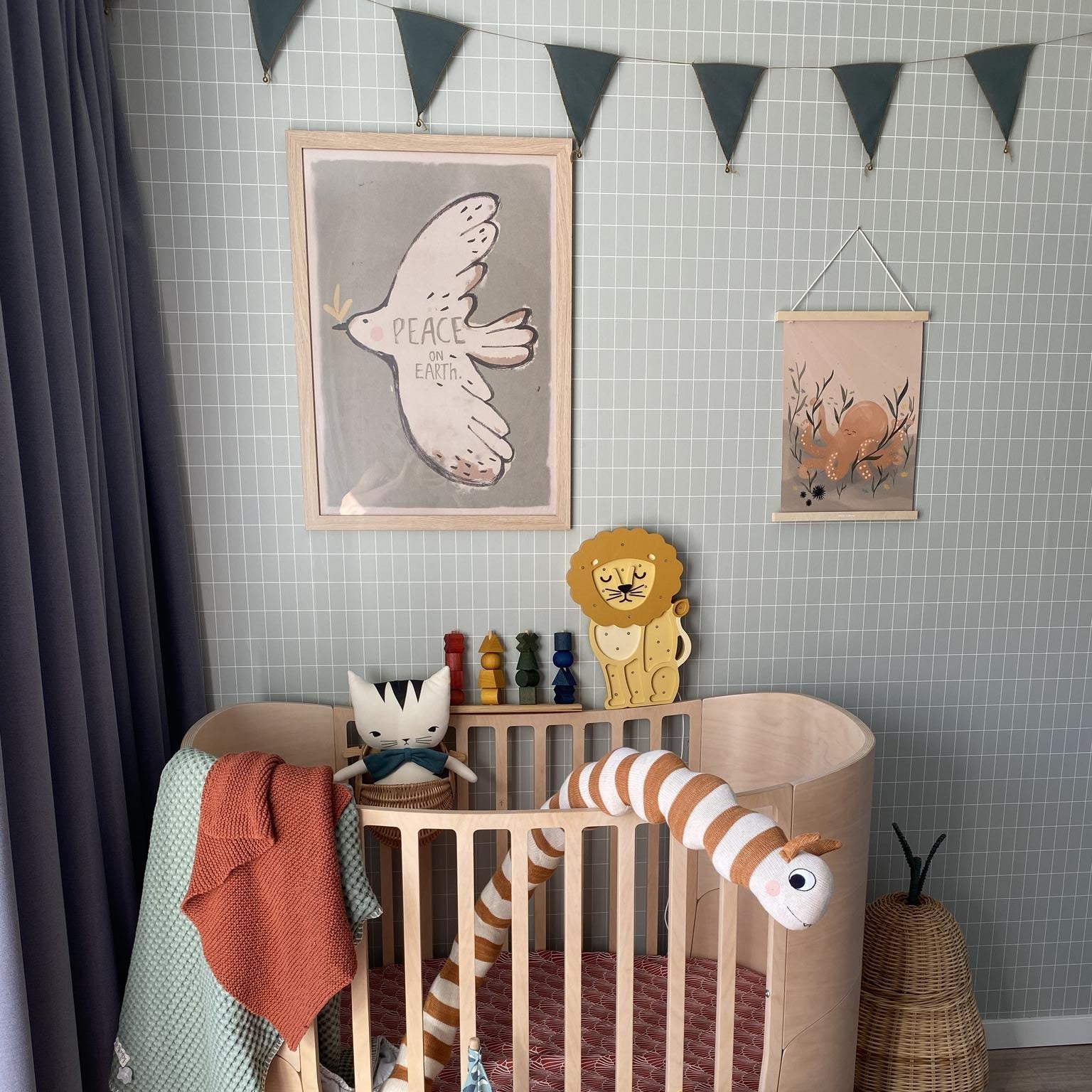 Little Lights yellow Lion Night Light next to a crib in a baby nursery