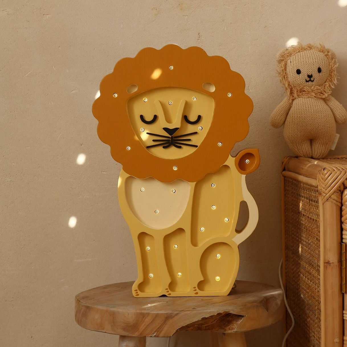 Little Lights Yellow Lion Night Limp on a wooden stool in a. baby room