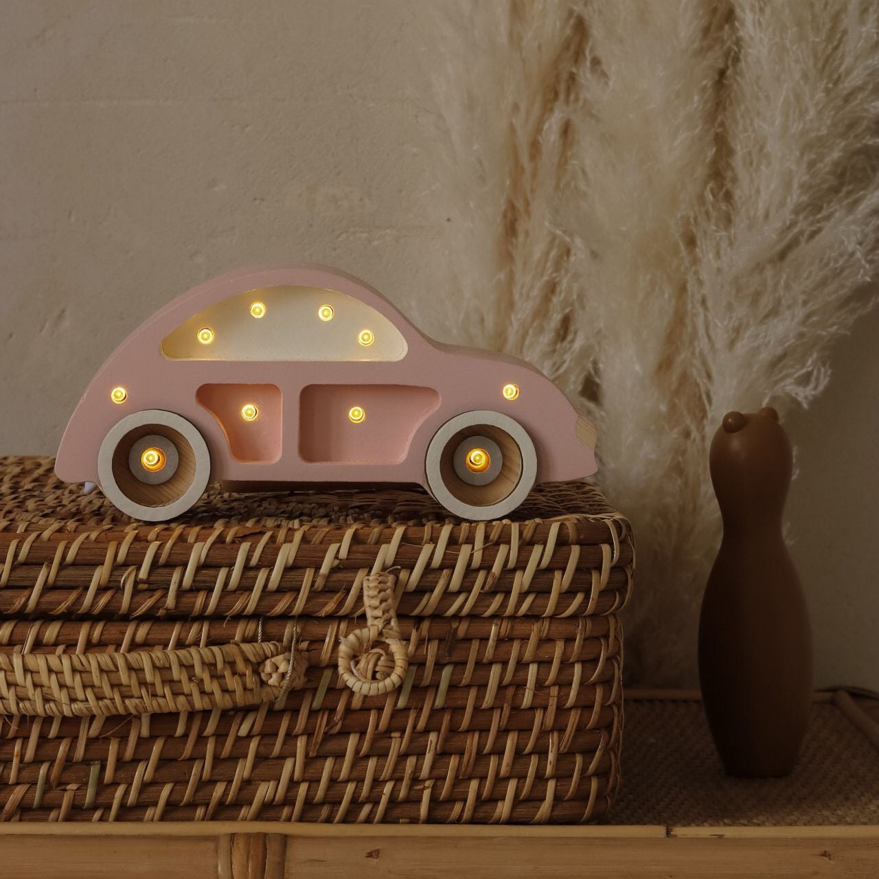 Pink Mini Beetle Car night light glowing softly on a wicker basket in a kid's room
