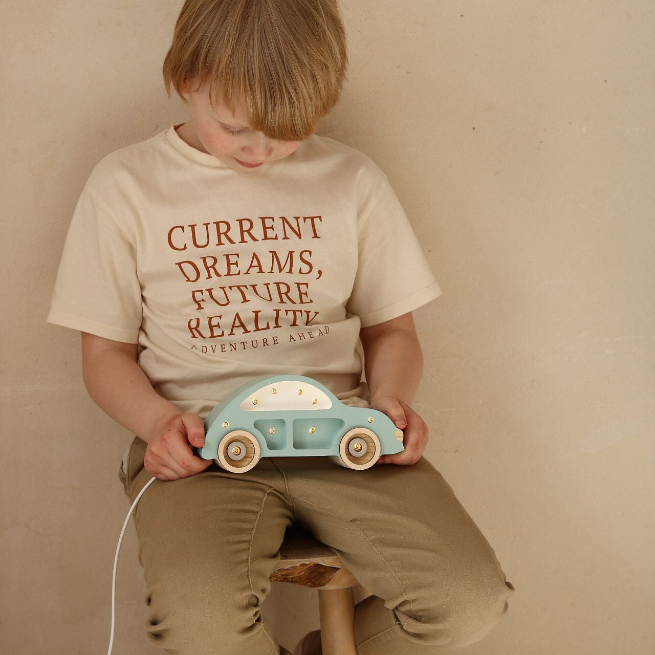 A boy holding Little Lights Mini Beetle Blue Car Lamp