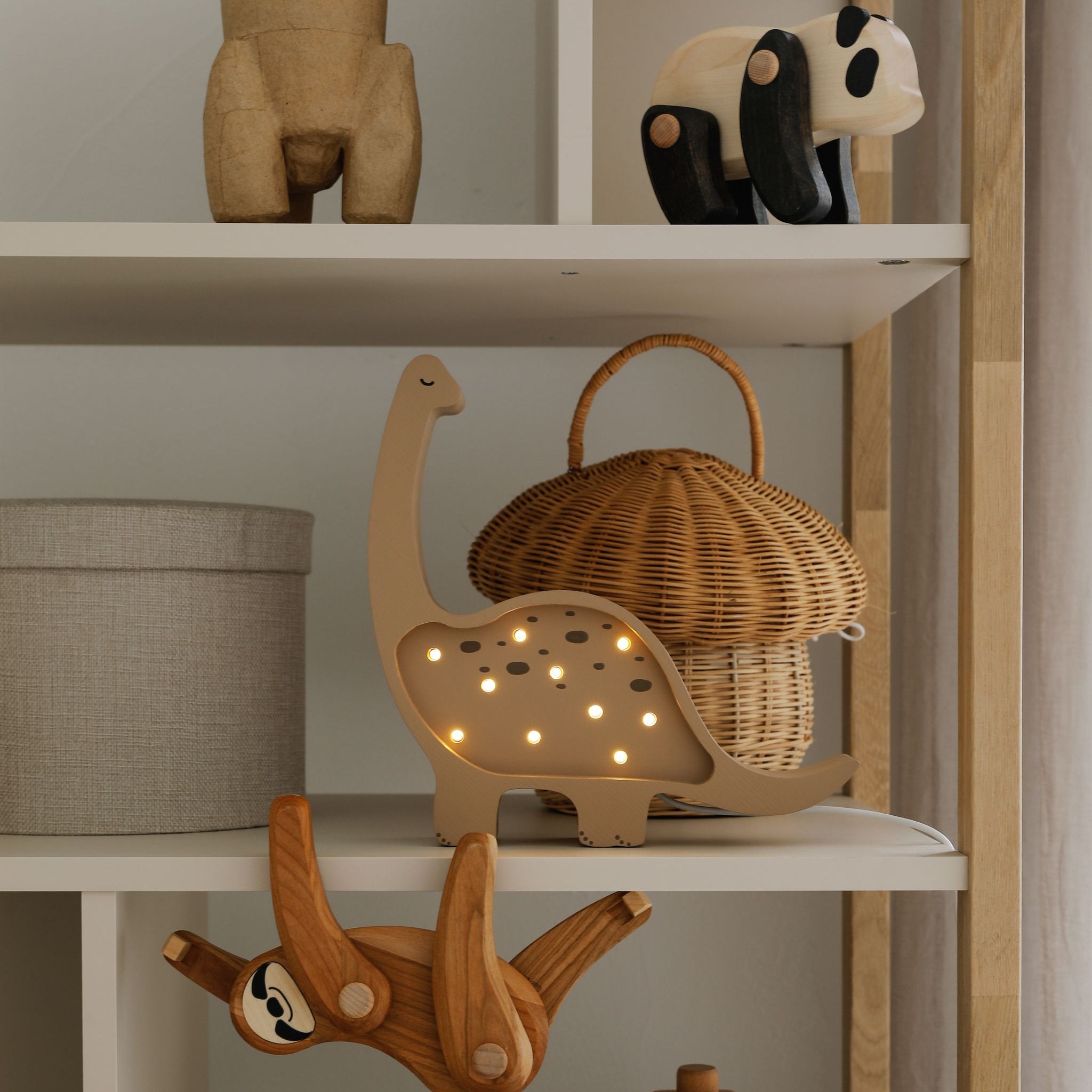 Little Lights Mini Dino brown lamp glowing on a shelf in a baby boy room