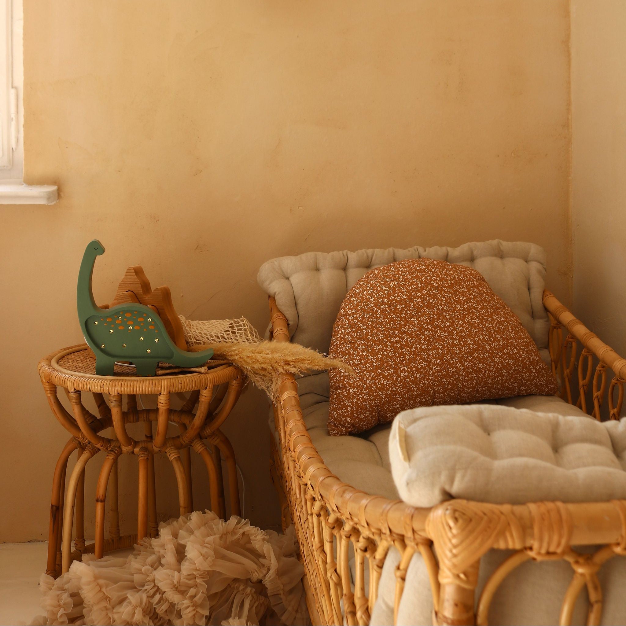 Mini Dinosaur Kids Lamp in a nursery with wicker crib, cushions, and decorative items against a beige wall.