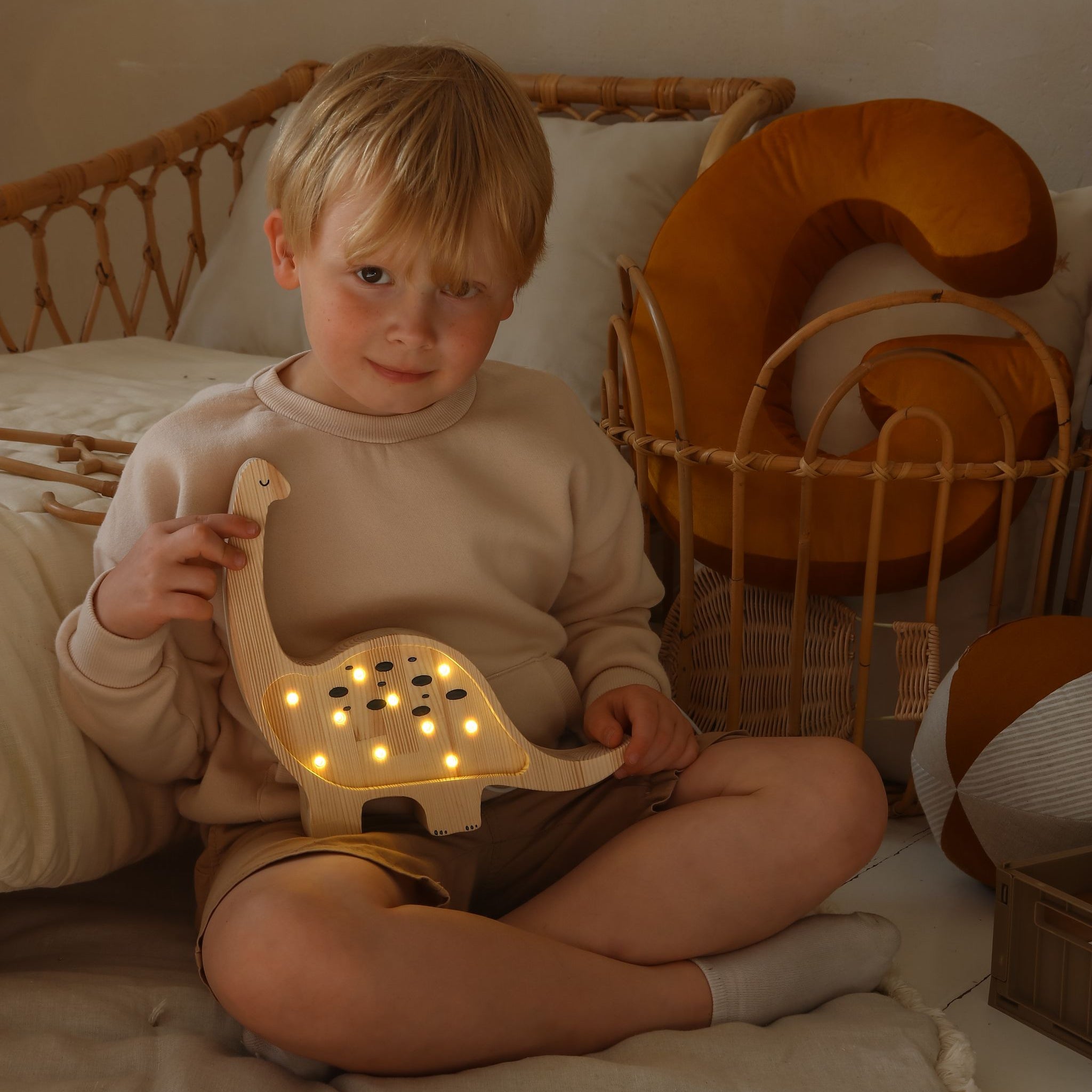A toddler boy holding Mini Dino wooden lamp