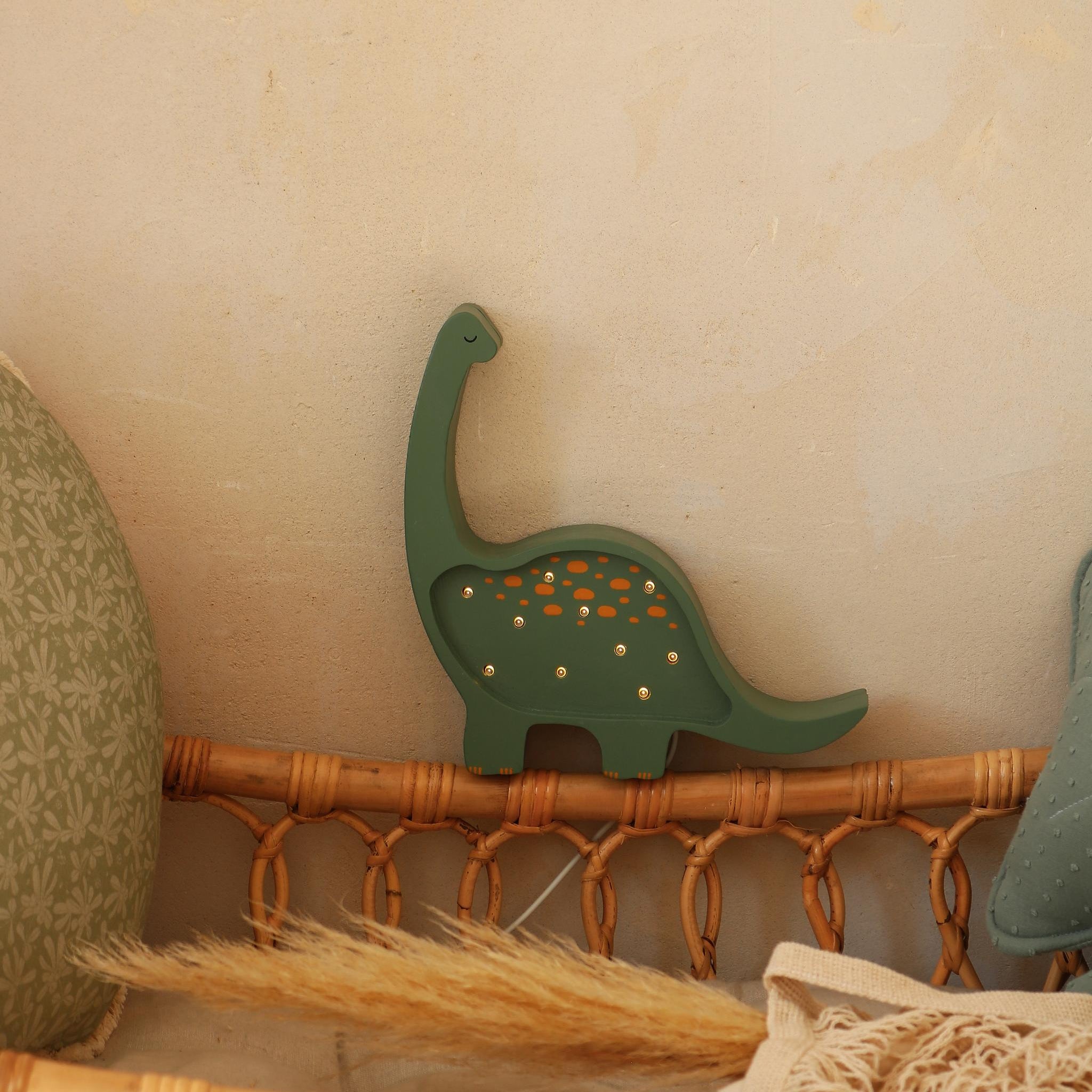Little Lights green Mini Dino Night Light by the crib in a baby nursery