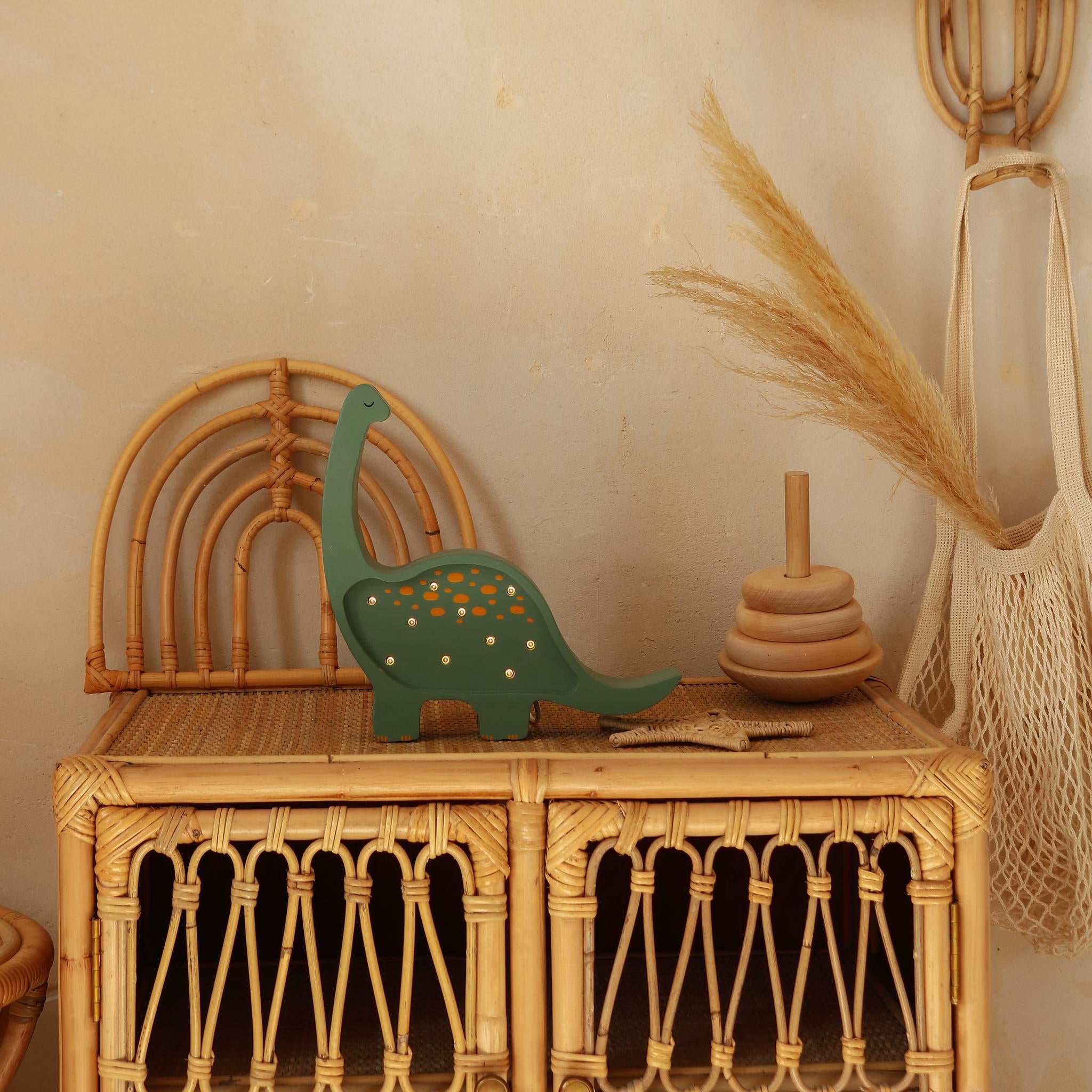Green Dino lamp on a wicker dresser in a baby boy room
