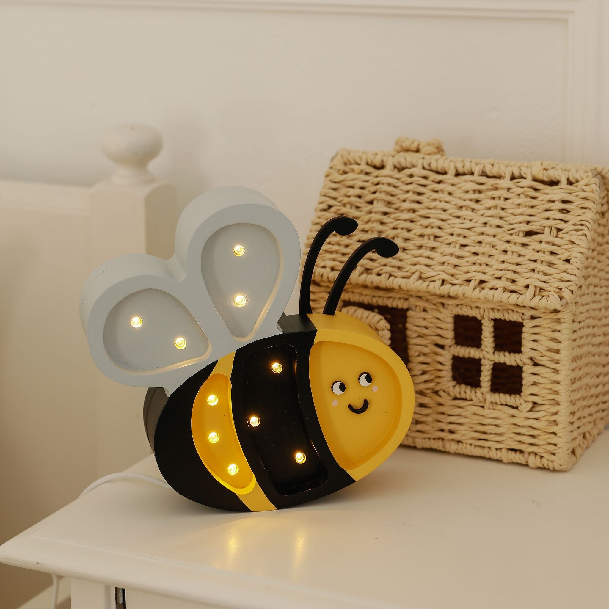 Little Lights Mini Happy Bee night light on a dresser by a bed in a kid's room