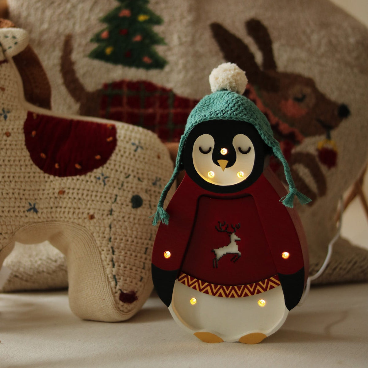 Little Lights red Holiday Penguin Lamp next to a cozy Christmas blanket