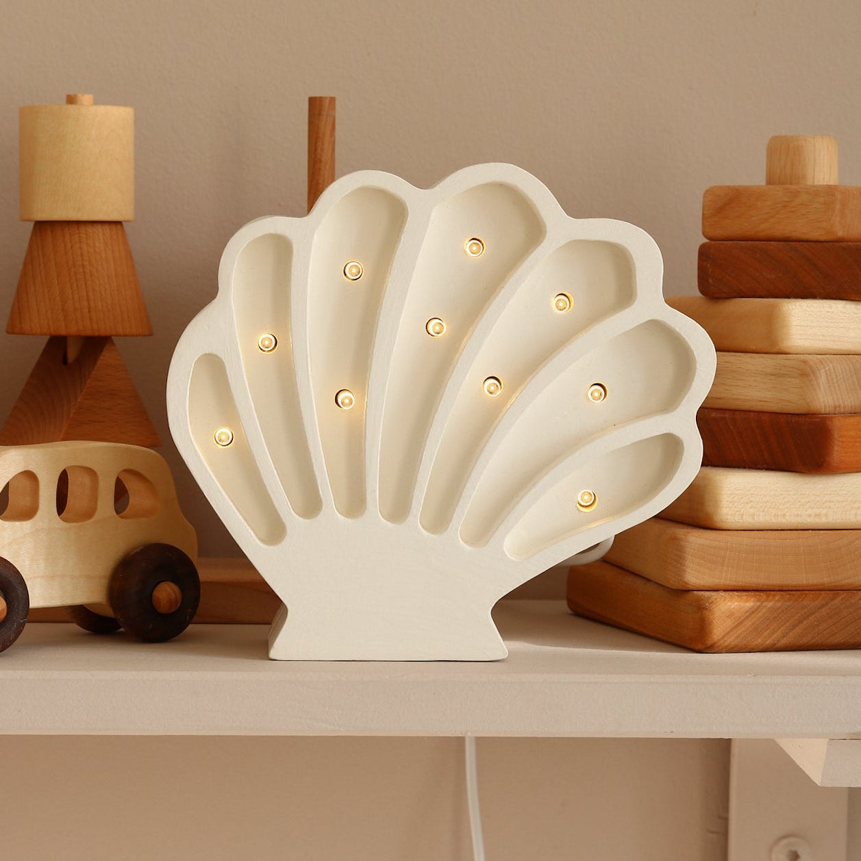 White Shell dimmable lamp by Little Lights with wooden toys on a shelf