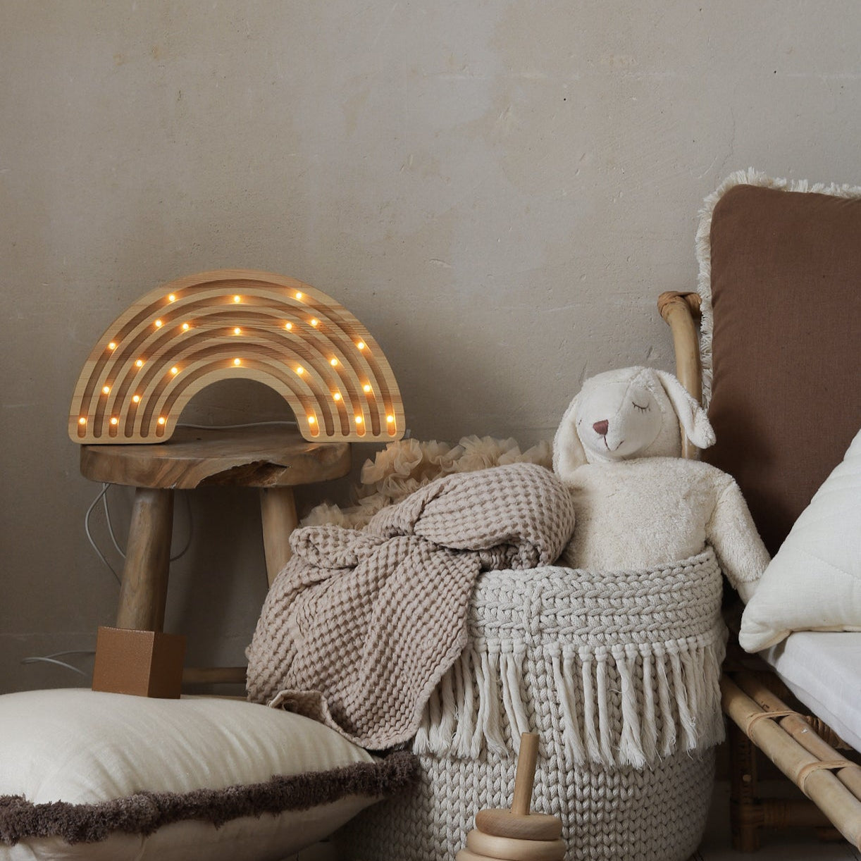 Little Lights wooden rainbow lamp in kid's room with plush toys, and a woven basket.