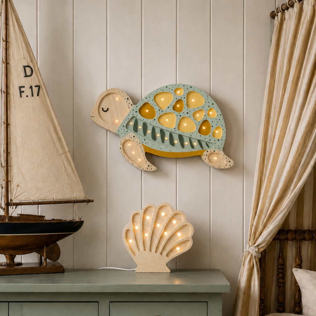 A styled bedroom corner featuring a light blue and yellow sea turtle wall light above a matching sage green dresser, alongside a glowing wooden seashell lamp, a wooden model sailboat, and beige curtains.