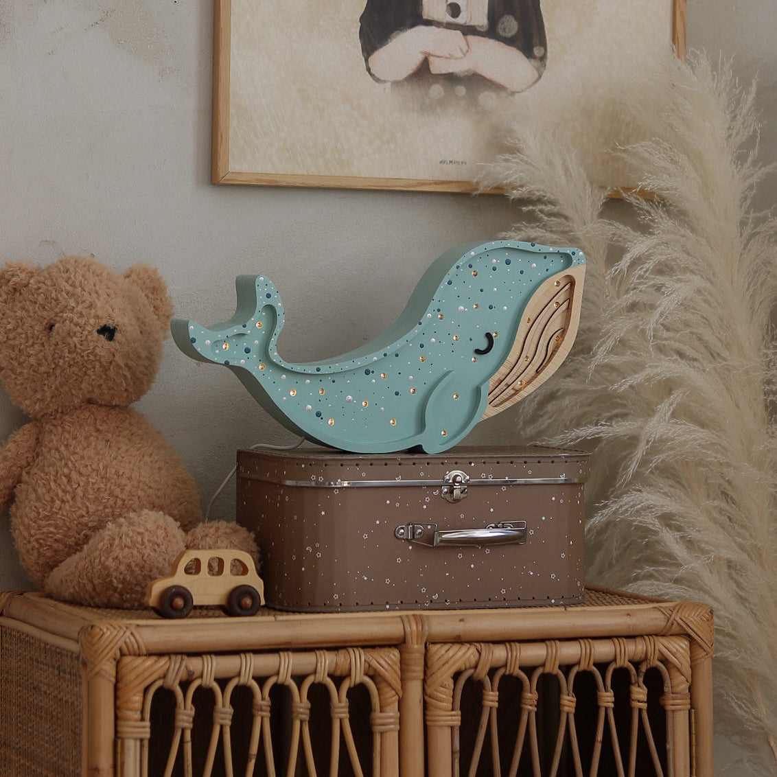 Light blue whale Night Light by Little Lights on a wicker cabinet in a baby room